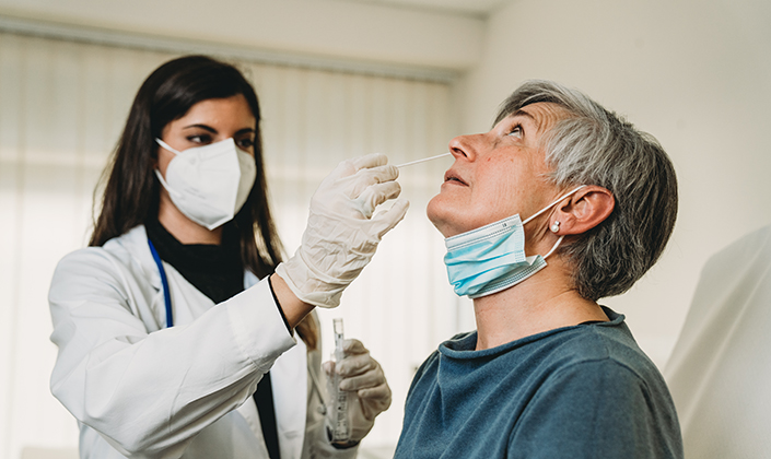 Medizinische Fachperson nimmt älterer Patientin Probe aus dem Nasen-Rachenraum für Coronatest